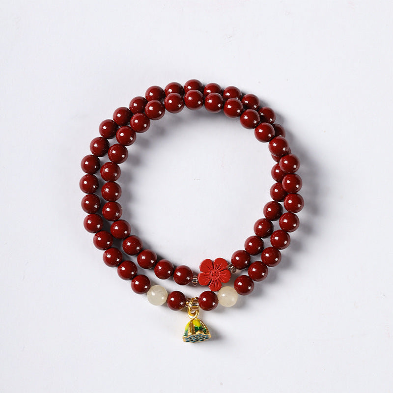 Double wrap cinnabar bracelet with lotus charm on white background