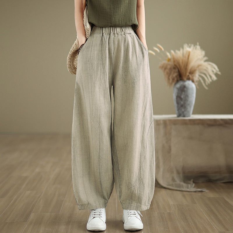 Model wearing oatmeal colored cotton linen harem pants with hands in pockets