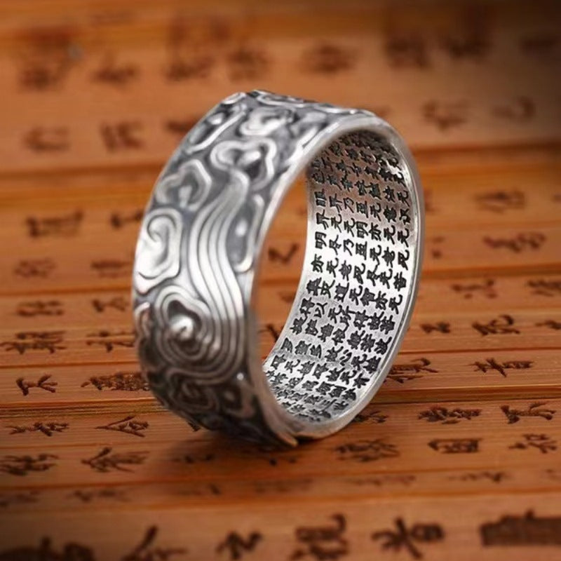 Close up view of a silver tone copper ring with cloud carvings and text engraving