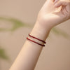 Close-up of a thin red garnet beaded bracelet on a wrist