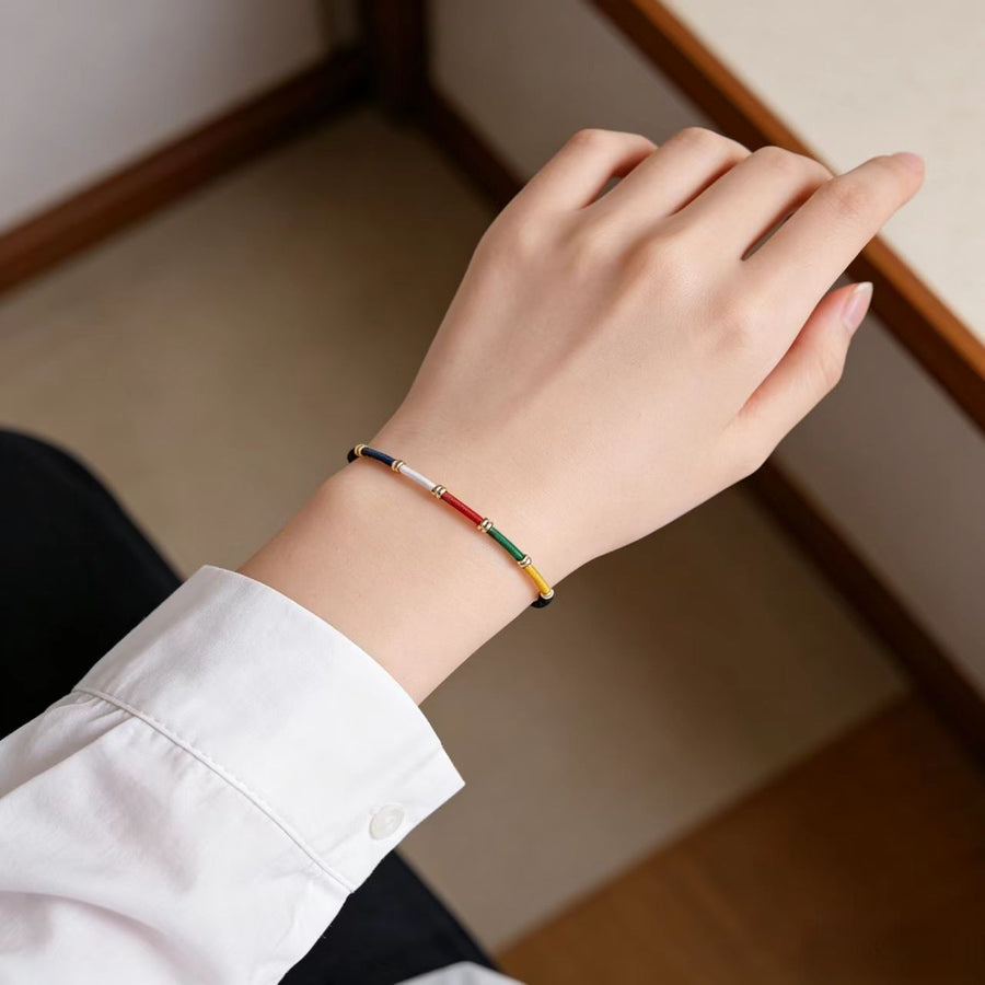 Close up of a wrist wearing a multicolored woven cord bracelet