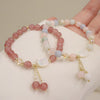 Pink strawberry quartz beaded bracelet with a white shell cat charm and dangling beads