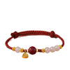 Close up of a red string bracelet with a cinnabar lotus bead on a wrist