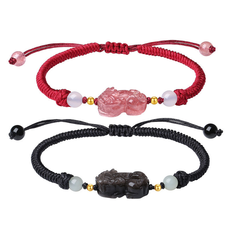 Two hands holding showing matching Pixiu bracelets, one black and one pink