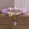 Close up of lavender amethyst beaded bracelet with white flower beads and gold charm