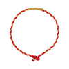 Close up of a wrist wearing a red and gold braided bracelet with a textured metal tube center
