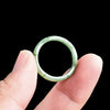 Close up of a green jade ring carved with a bamboo pattern held between fingers