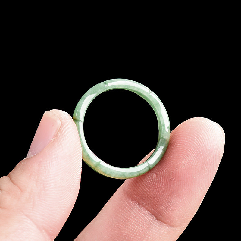Close up of a green jade ring carved with a bamboo pattern held between fingers