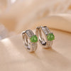 Pair of sterling silver hoop earrings with green jade beads on beige fabric