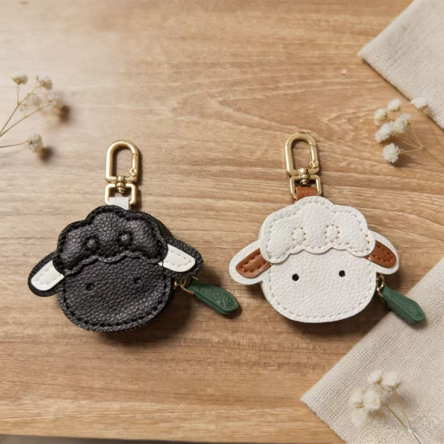 Black and white sheep face coin purse keychains on a wooden table
