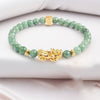 Close-up of a green jade beaded bracelet with a gold-tone Pixiu charm on a white background