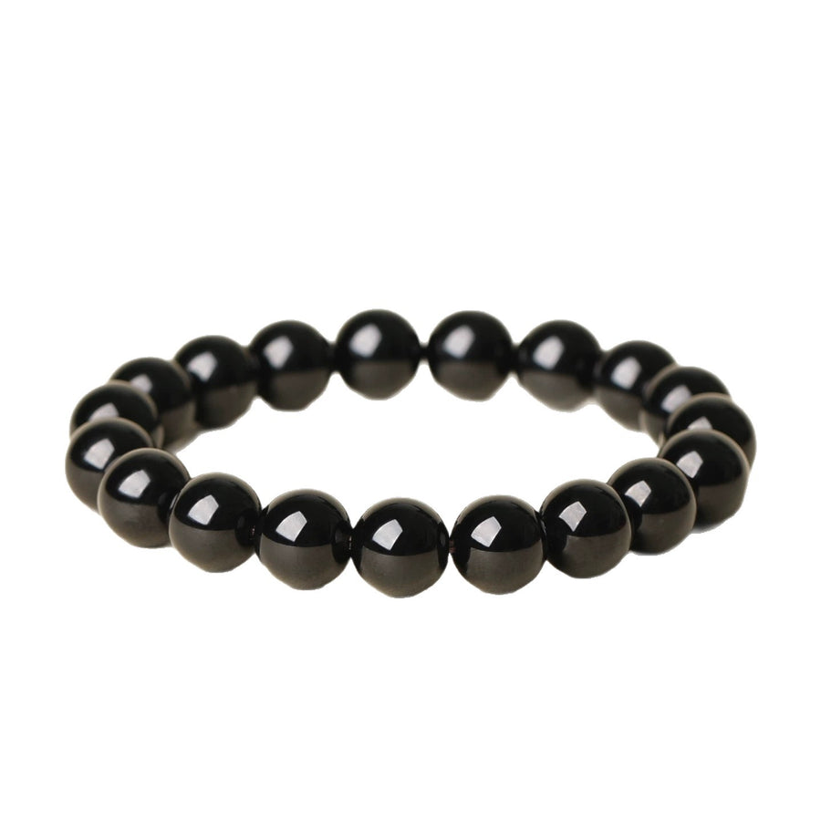 A close-up view of a polished black obsidian beaded bracelet on a white background