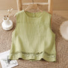 Light green sleeveless tank top with geometric embroidery on the hem hanging on a wooden hanger