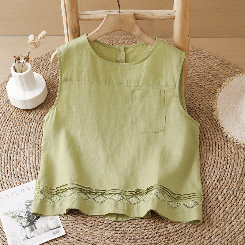 Light green sleeveless tank top with geometric embroidery on the hem hanging on a wooden hanger