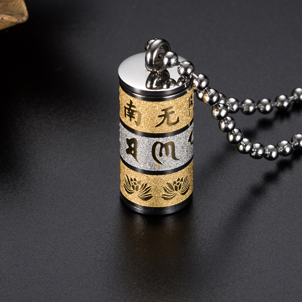 Close-up of a silver and gold cylindrical prayer wheel pendant with mantras and lotus flowers