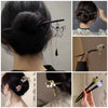 Back view of a woman wearing a black wooden hairpin with a silver butterfly charm in her dark hair bun.