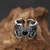 Close up of a silver tone adjustable copper ring with a swirling floral pattern and a black stone center