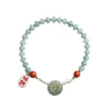 Hand holding a jade bead bracelet with a green peace buckle and red agate stones