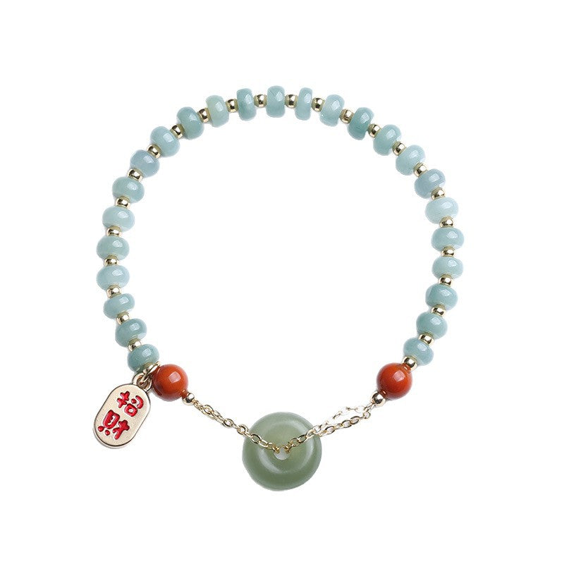 Hand holding a jade bead bracelet with a green peace buckle and red agate stones
