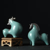 A teal ceramic horse figurine with a crackled glaze finish sitting on a dark surface