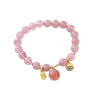 Pink strawberry quartz beaded bracelet with gold charms on a white background