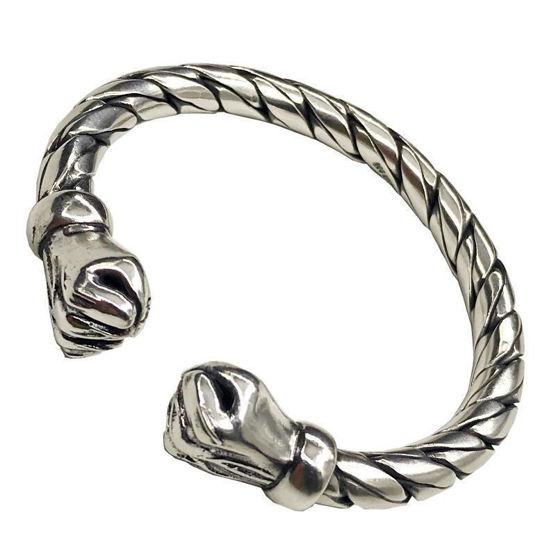 Silver tone twisted open cuff bracelet with animal head terminals on white background