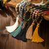 Assortment of long beaded necklaces with colorful tassels on wood