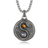 Close up of round copper pendant with snake yin yang design and two stones