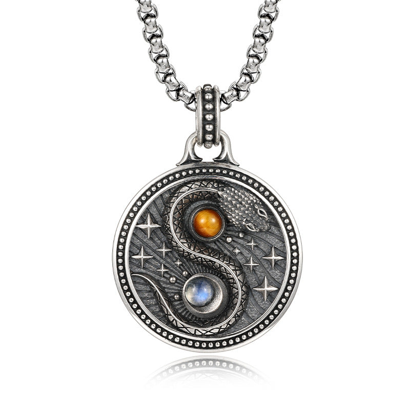 Close up of round copper pendant with snake yin yang design and two stones