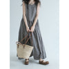 Woman wearing a grey plaid sleeveless midi dress holding a straw bag