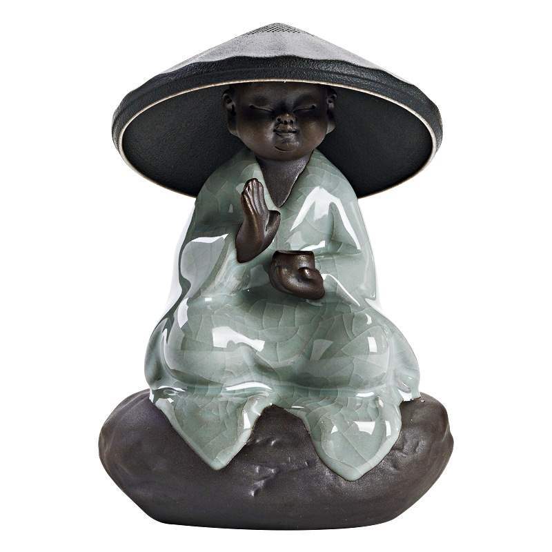 Green glazed ceramic monk figurine wearing a wide hat acting as a tea strainer
