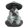 Green glazed ceramic monk figurine wearing a wide hat acting as a tea strainer