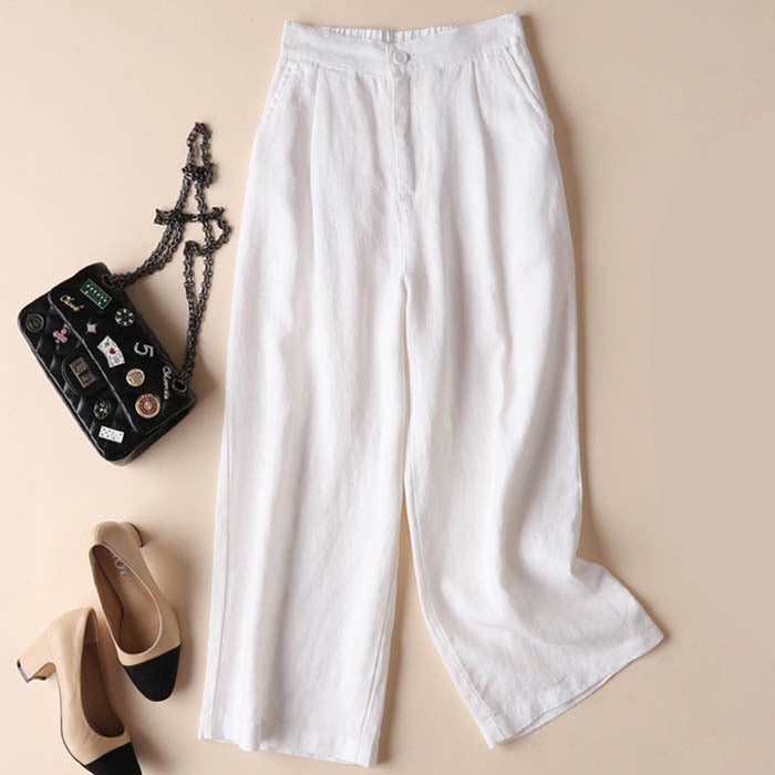 Flat lay view of white wide leg linen pants next to shoes and a bag