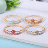 Four gold-tone wire bangle bracelets with colorful crystal beads resting on an open book