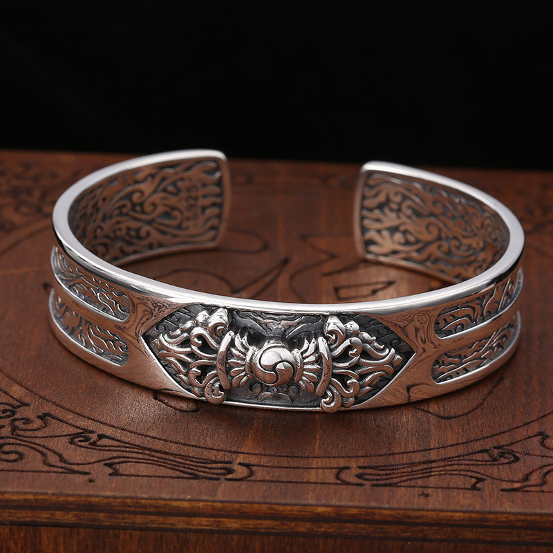 Close up view of a silver open cuff bracelet with engraved deer pattern