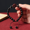 Close-up of a dark ebony wood beaded bracelet with a carved rose charm held in hand