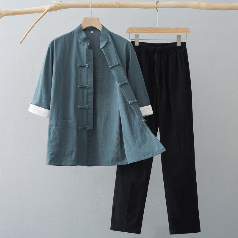A teal green traditional Chinese style half sleeve top and black pants hanging on a wooden rack