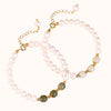 Two bracelets showing white pearls and green jade beads on a light background