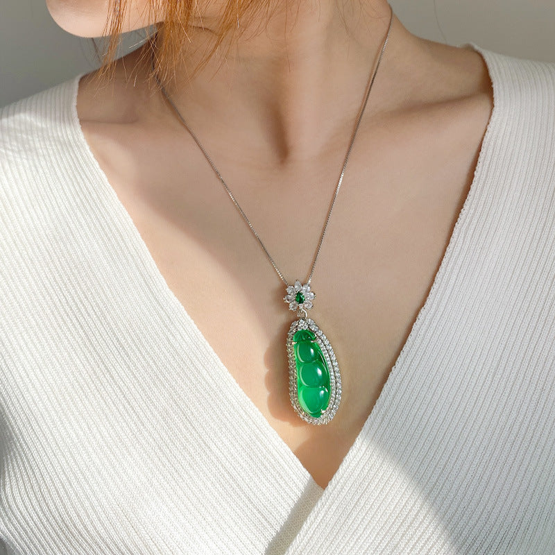 Green fortune bean pendant necklace worn against a white top