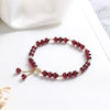 Close-up of a red imitation garnet beaded bracelet with gold-tone metal details on a white surface