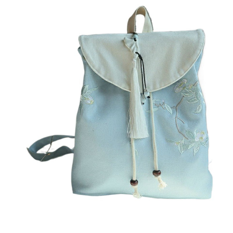 Light blue embroidered canvas backpack with white flap and tassel drawstring