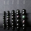 Five strands of black obsidian beads showing different sizes and rainbow eye colors on a display stand