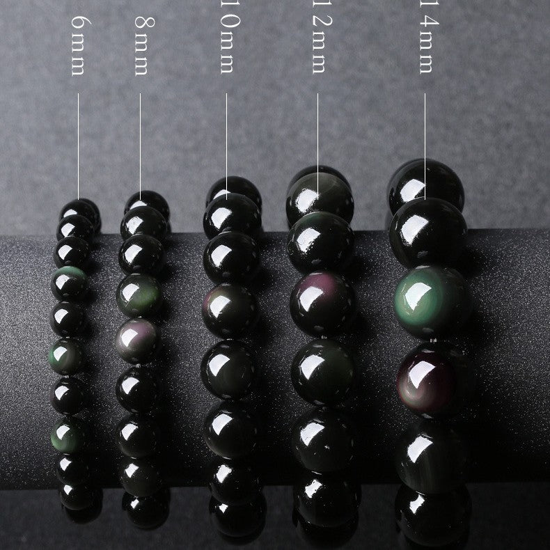 Five strands of black obsidian beads showing different sizes and rainbow eye colors on a display stand