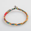 Close up view of a handmade multicolored braided bracelet with a silver clasp