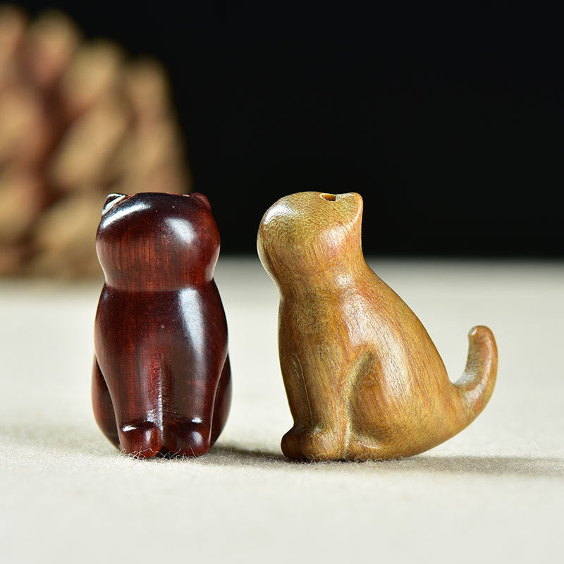Two small wooden carved cats sitting side by side on a table
