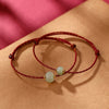Close up of red string bracelet with green jade lotus bead on brown paper background
