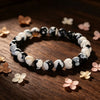 Close up of a black and white beaded bracelet on a wooden surface
