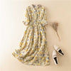 Flat lay of a yellow floral midi dress with white shoes and dried flowers