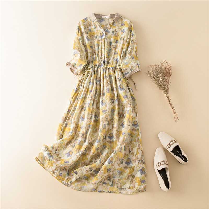 Flat lay of a yellow floral midi dress with white shoes and dried flowers