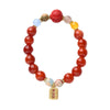 A hand holding a red agate beaded bracelet with a gold-tone peace talisman charm